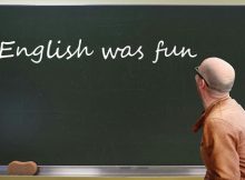 Lehrer vor Tafel, auf der 'English was fun' steht