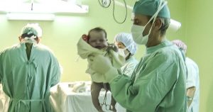 Neugeborenes Baby in den Händen eines Spitalsarztes